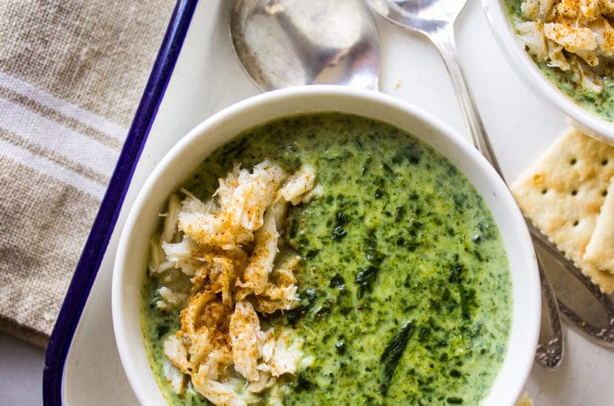 Overhead photo of creamy spinach soup with crabmeat with two spoons and crackers