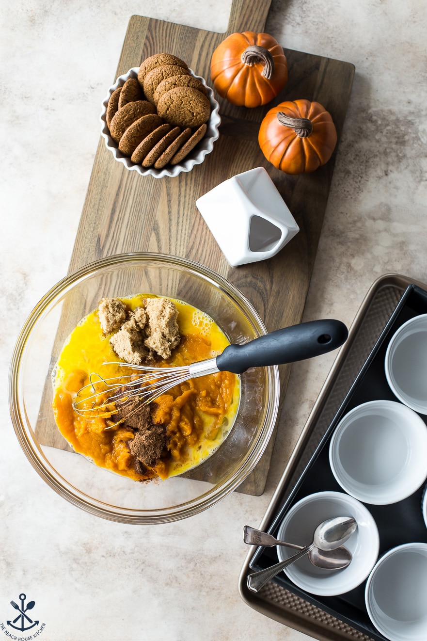 Ingredients for Pumpkin Custards with Gingersnap Crumble in a bowl with a whisk