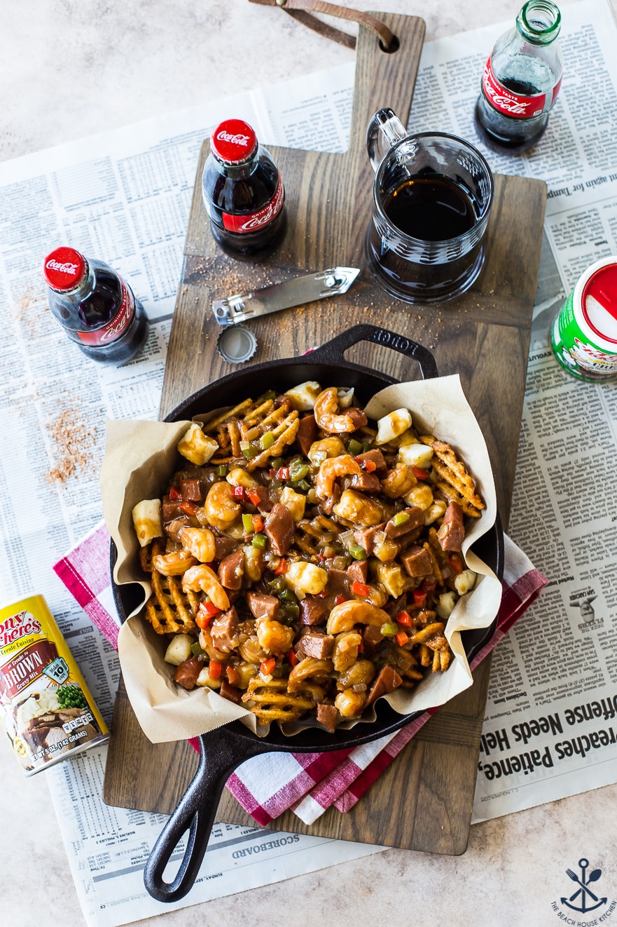 Overhead photo of Cajun poutine in a skillet on a wooden board