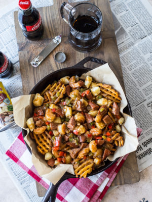 Overhead photo of Cajun poutine in a skiller on a wooden board