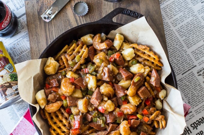 Overhead photo of Cajun poutine in a skiller on a wooden board