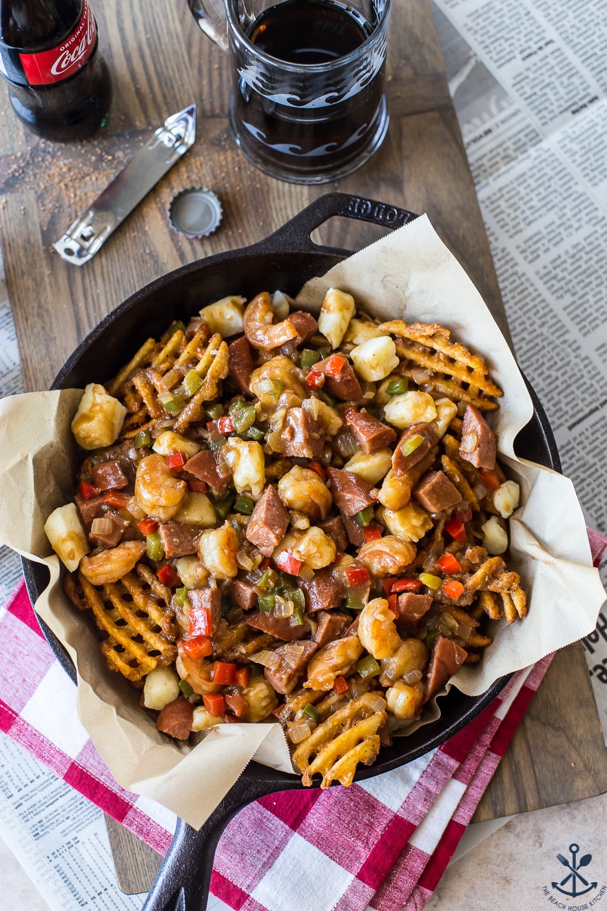 Overhead photo of Cajun poutine in a skillet on a wooden board