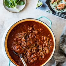 Short Rib Ragù in a Dutch oven with a small plate of basil leaves