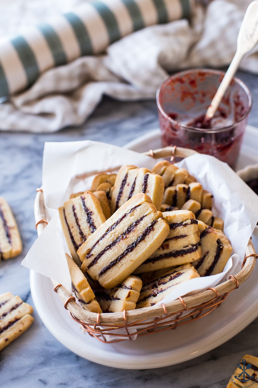 A baskey filled with Cherry Ribbon Butter Cookies with jam in the background