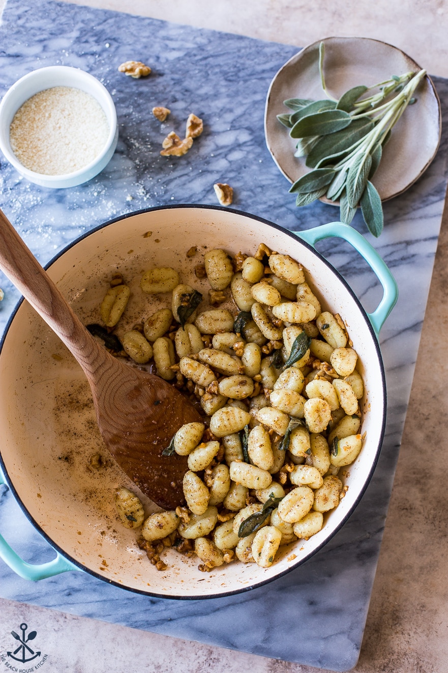 Pot filled with Gnocchi with Walnut Brown Butter Sage Sauce on a marble board