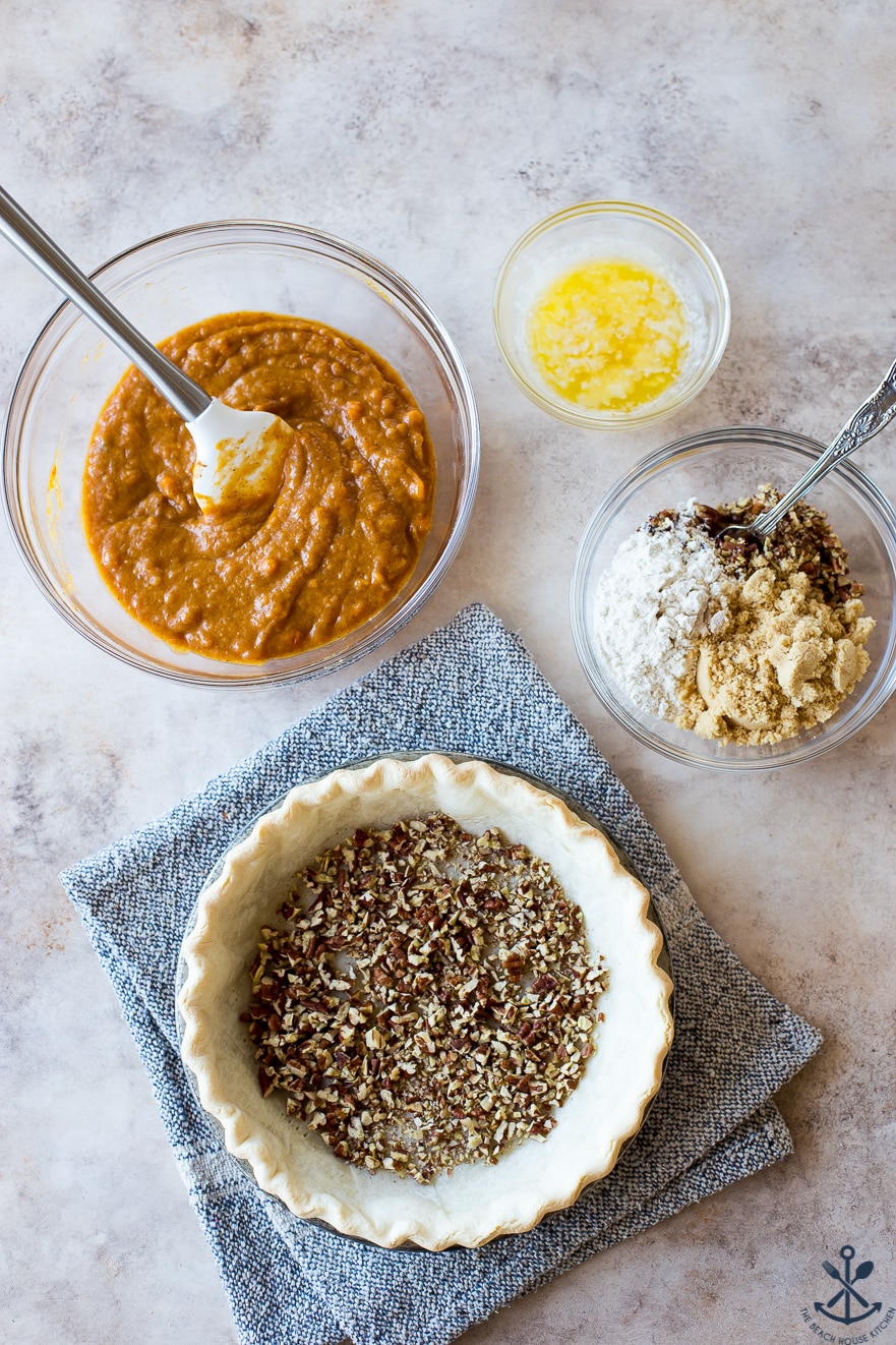 Overhead photo of pie crust filled with pecans and bowls with filling and topping ingredients