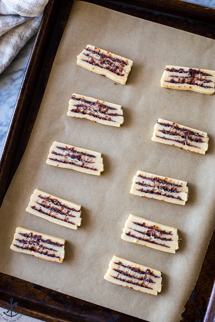 An overhead photo of pre-baked cherry ribbon butter cookies on a baking sheet lined with parchment