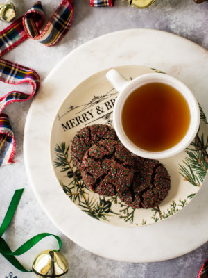 Overhead photo of a plate of 3 chewy chocolate gingersnap cookies with a cup of tea