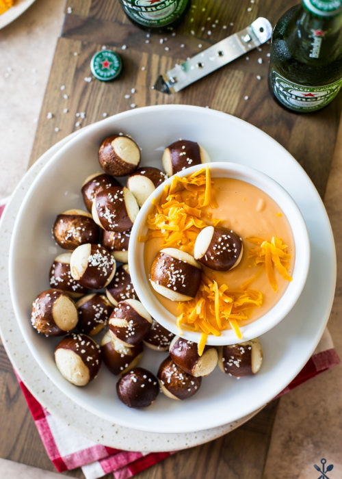 Easy Creamy Beer Cheese Dip in a bowl surrounded by pretzel nuggets