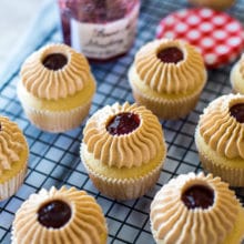 Peanut Butter and Jelly Cupcakes on a wire rack with a jar of strawberry preserves