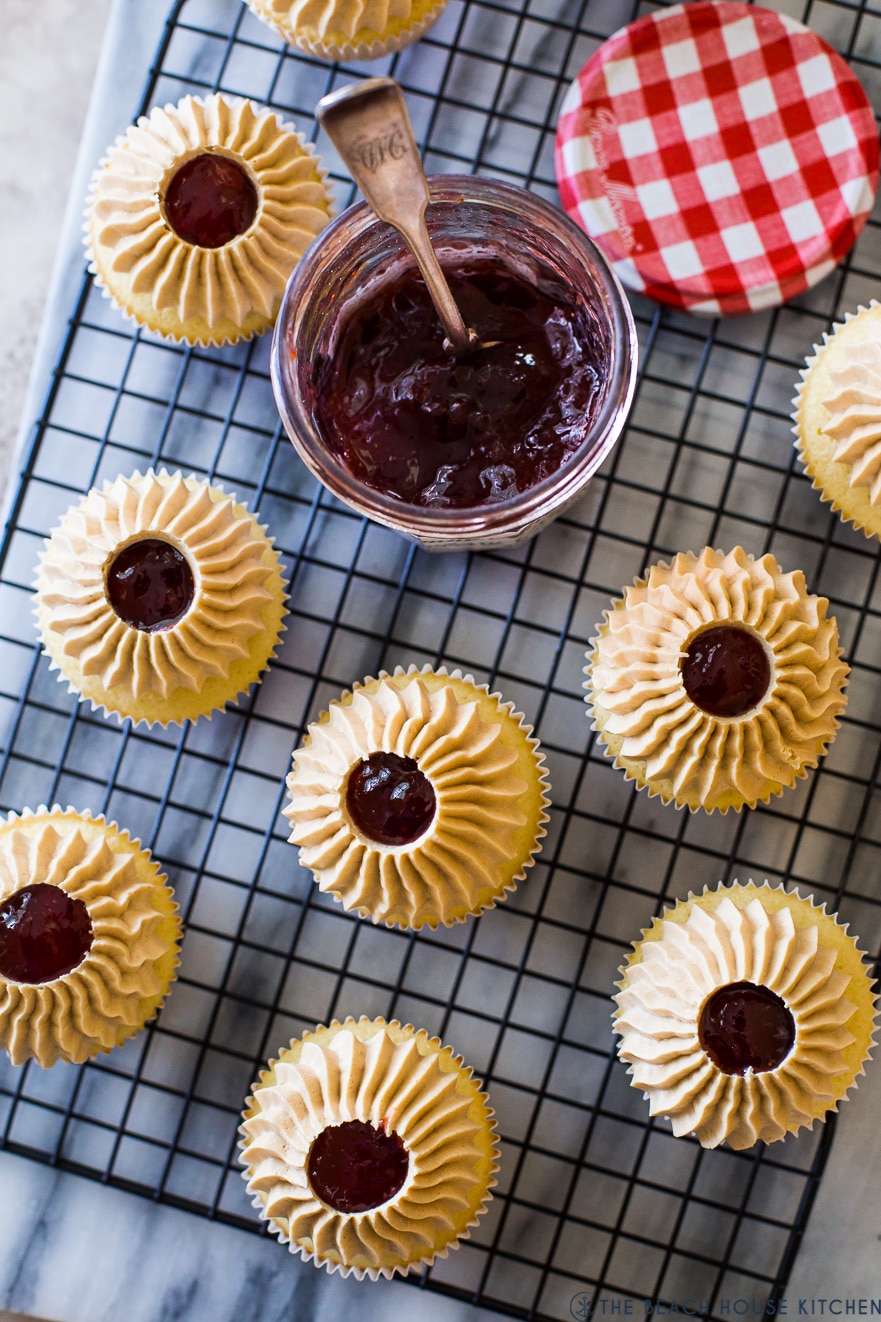 Up close overhead photo of cupcakes on a wire rack with a jar of preserves