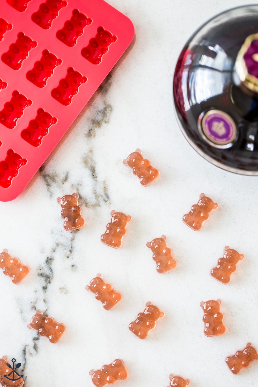 Up close overhead photo of gummies bears on a marble background with a gummie bear tray and a bottle of Chambord