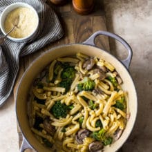 Overhead photo of a pot filled with Creamy Garlic Broccoli Mushroom Pasta on a wooden board