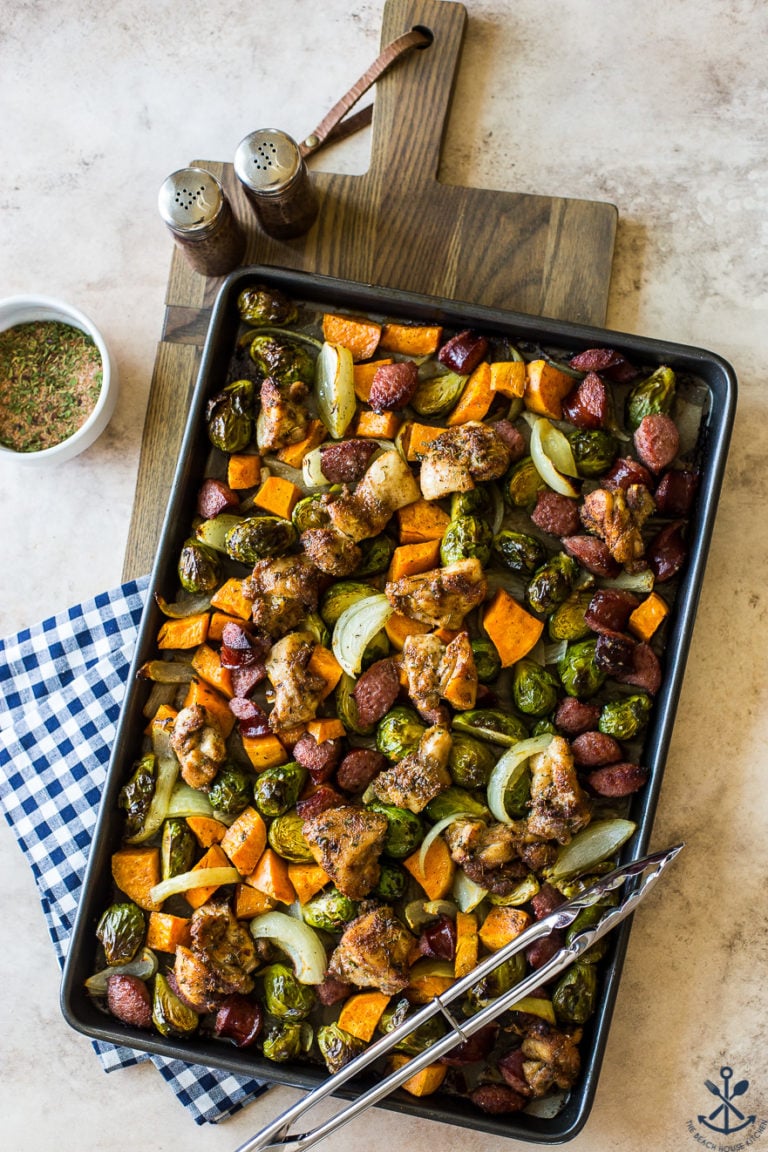 Overhead photo of sheet pan filled with jerk chicken, sweet potatoes, onions and Brussels sprouts