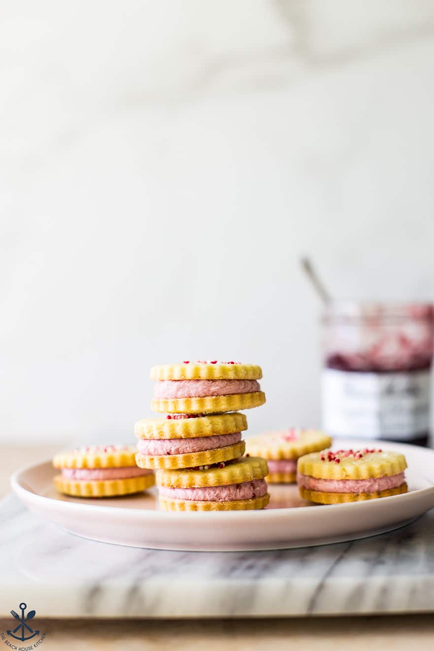 A plate of stacked Key Lime Sandwich Cookies with Raspberry Buttercream