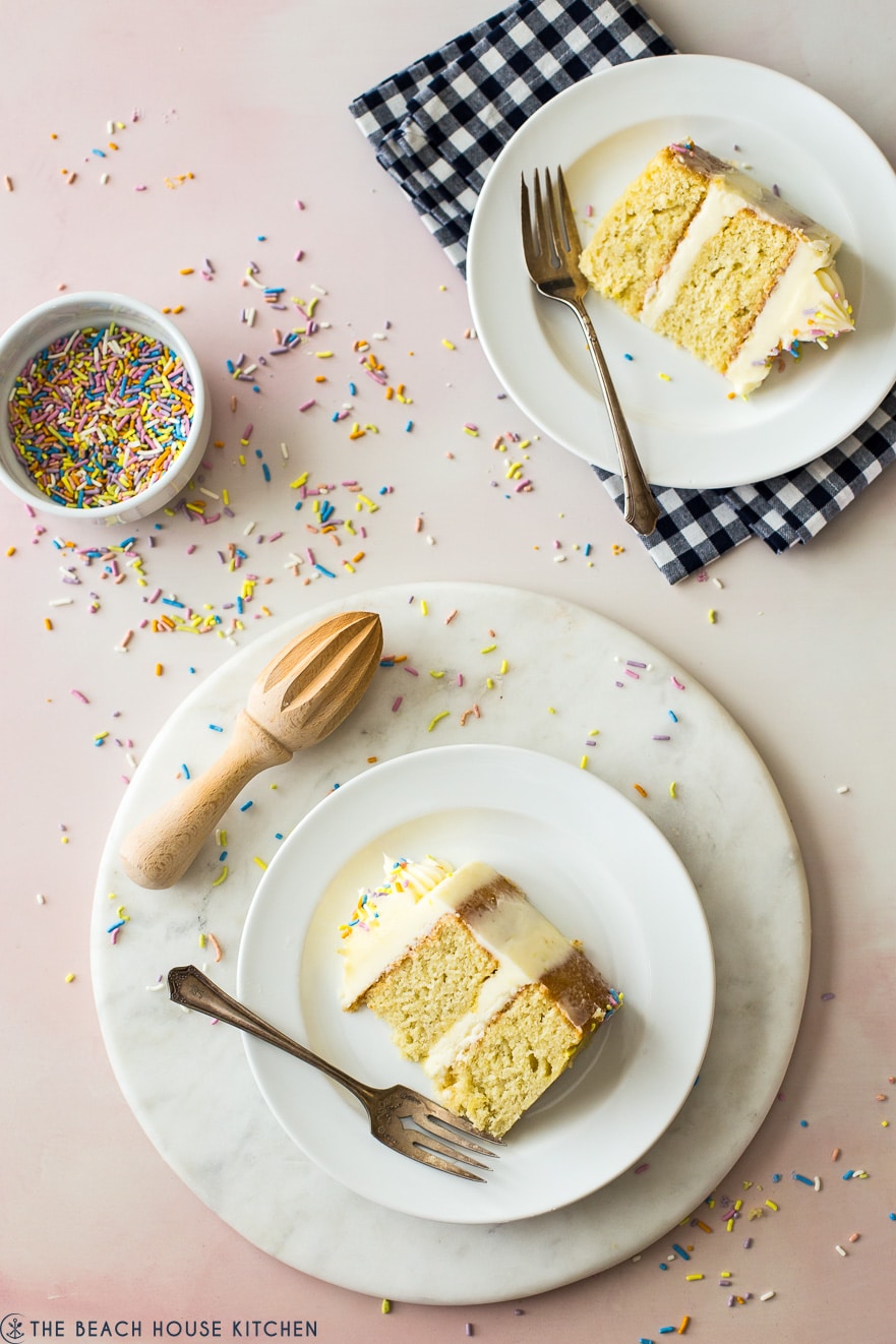 Overhead photo of lemon cake slices on plates with forks and a small bowl of pastel sprinkles
