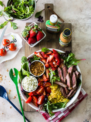 Overhead photo of a steak salad with corn and strawberries