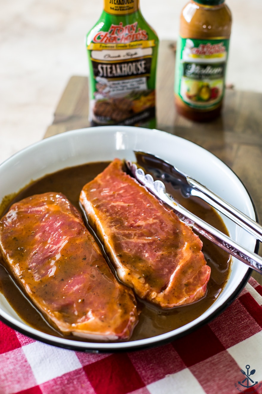 Photo of two steak marinating in a round enamel pan