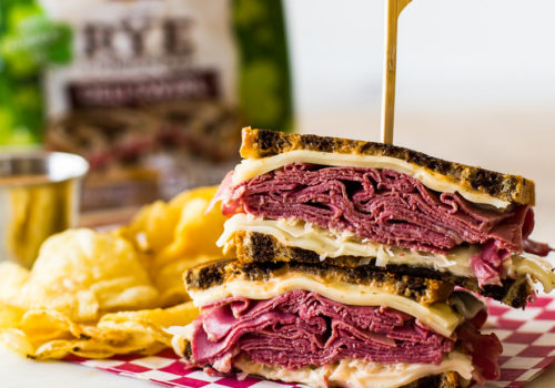 Classic Reuben Sandwich with chips and a loaf of rye bread in the background