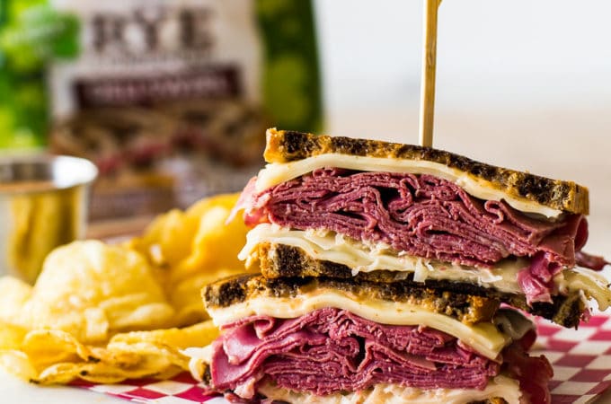 Classic Reuben Sandwich with chips and a loaf of rye bread in the background