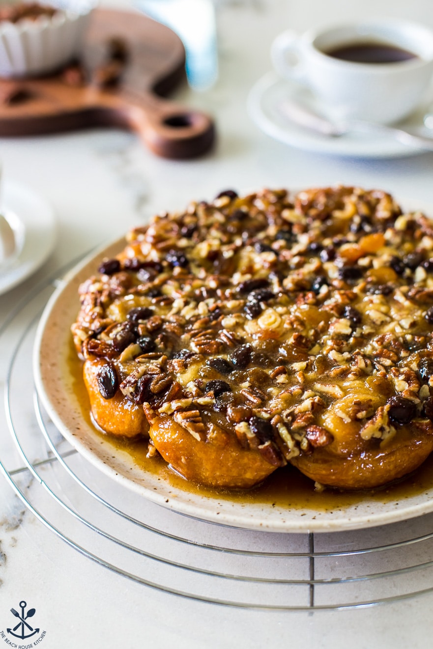 Easy Pecan Raisin Sticky Buns on a plate on a wire rack topped with pecans 