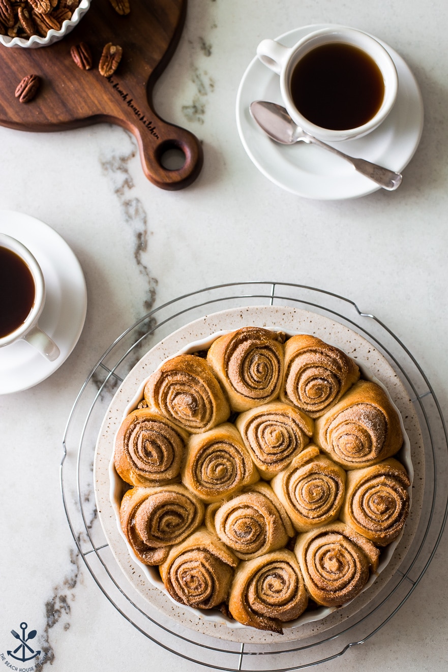 Overhead photo of sticky buns in a baking dish with a cup of coffee next to the dish