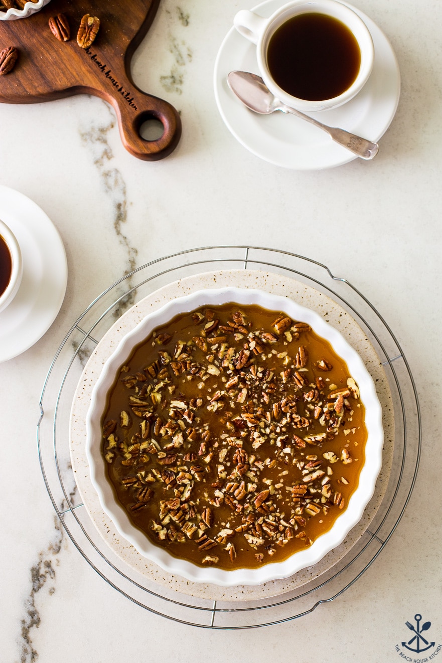 Overhead photo of a round dish filled with pecans in a caramel sauce