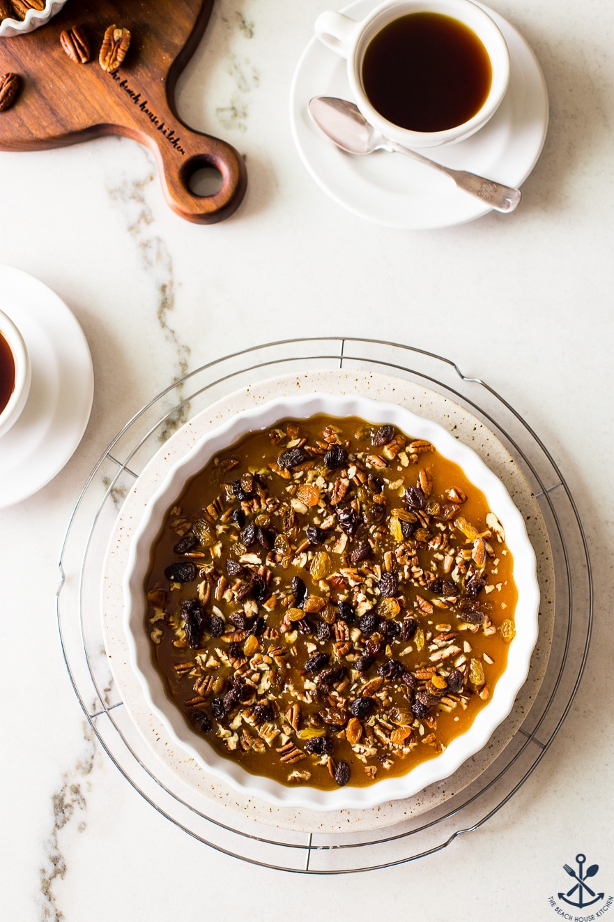 Overhead photo of a round baking dish with pecans and raisins and caramel sauce 
