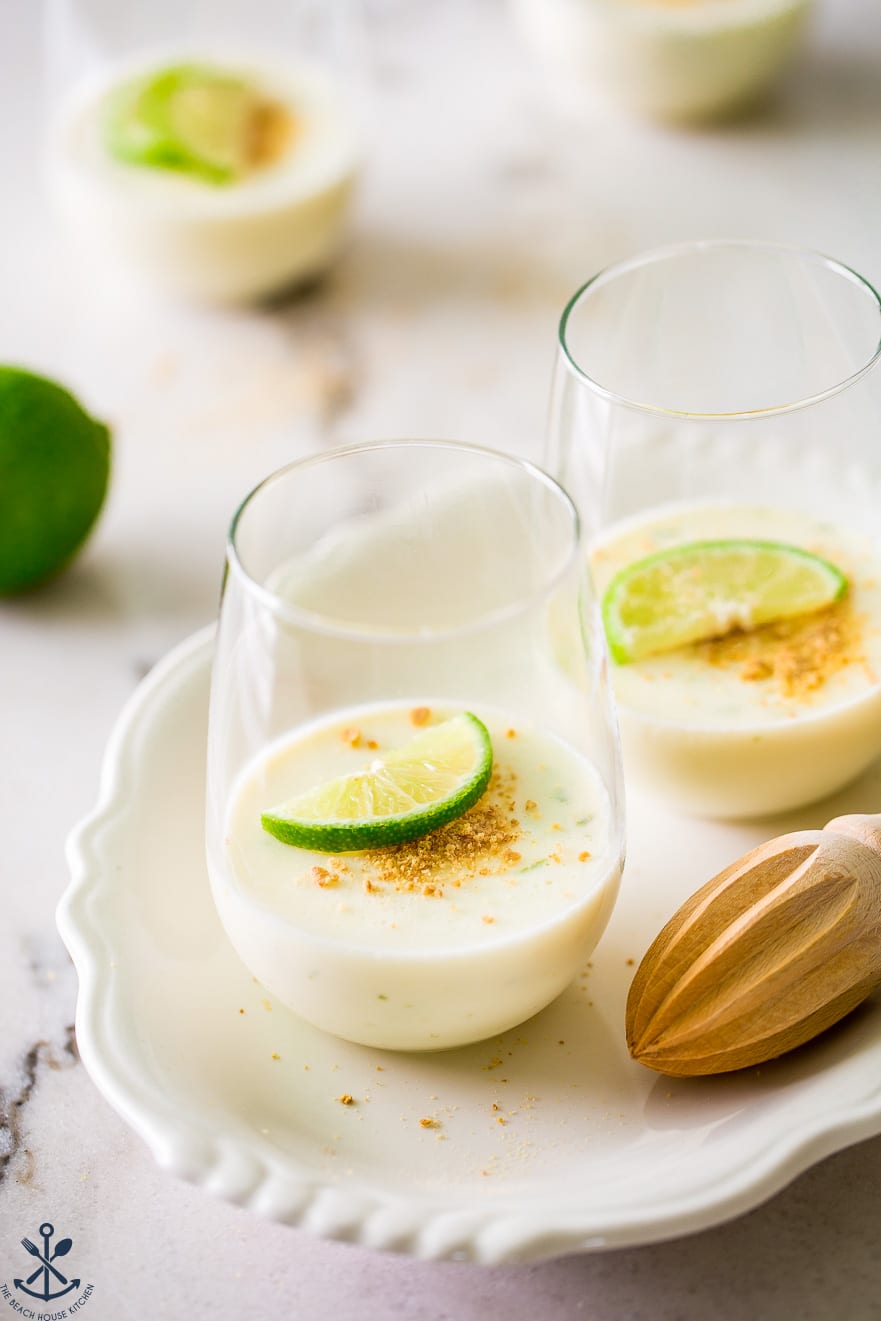 Two glasses filled with key lime panna cotta on a white oval plate