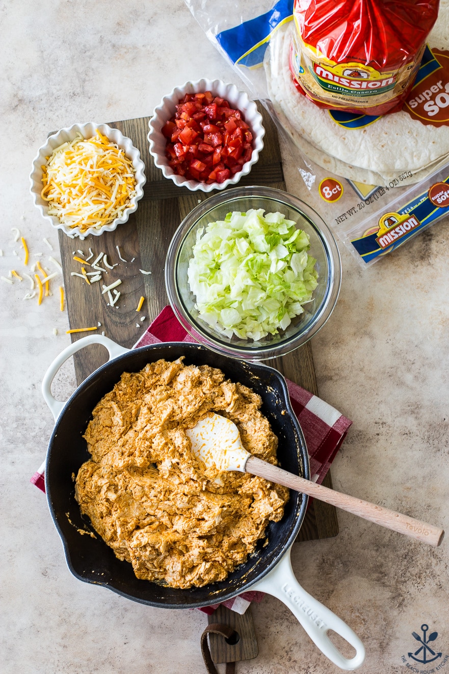 Overhead photo of ingredients for cunchwraps in bowls and a skillet on a wooden board