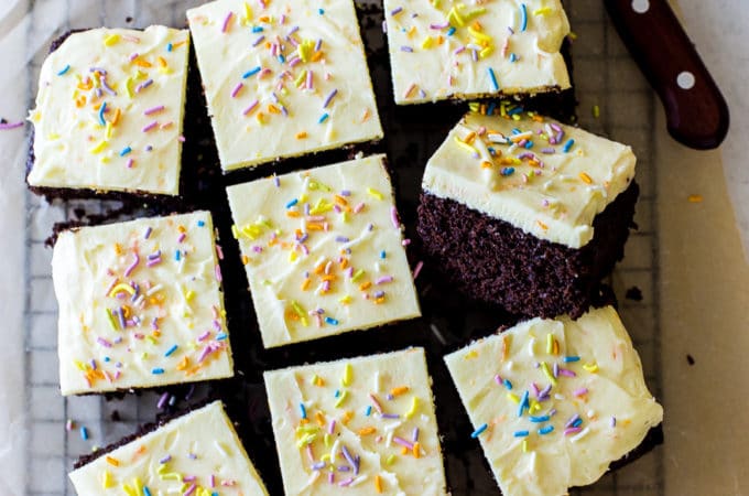 Overhead of the photo of iced chocolate cake surrounded by orange slices and a sharp knife