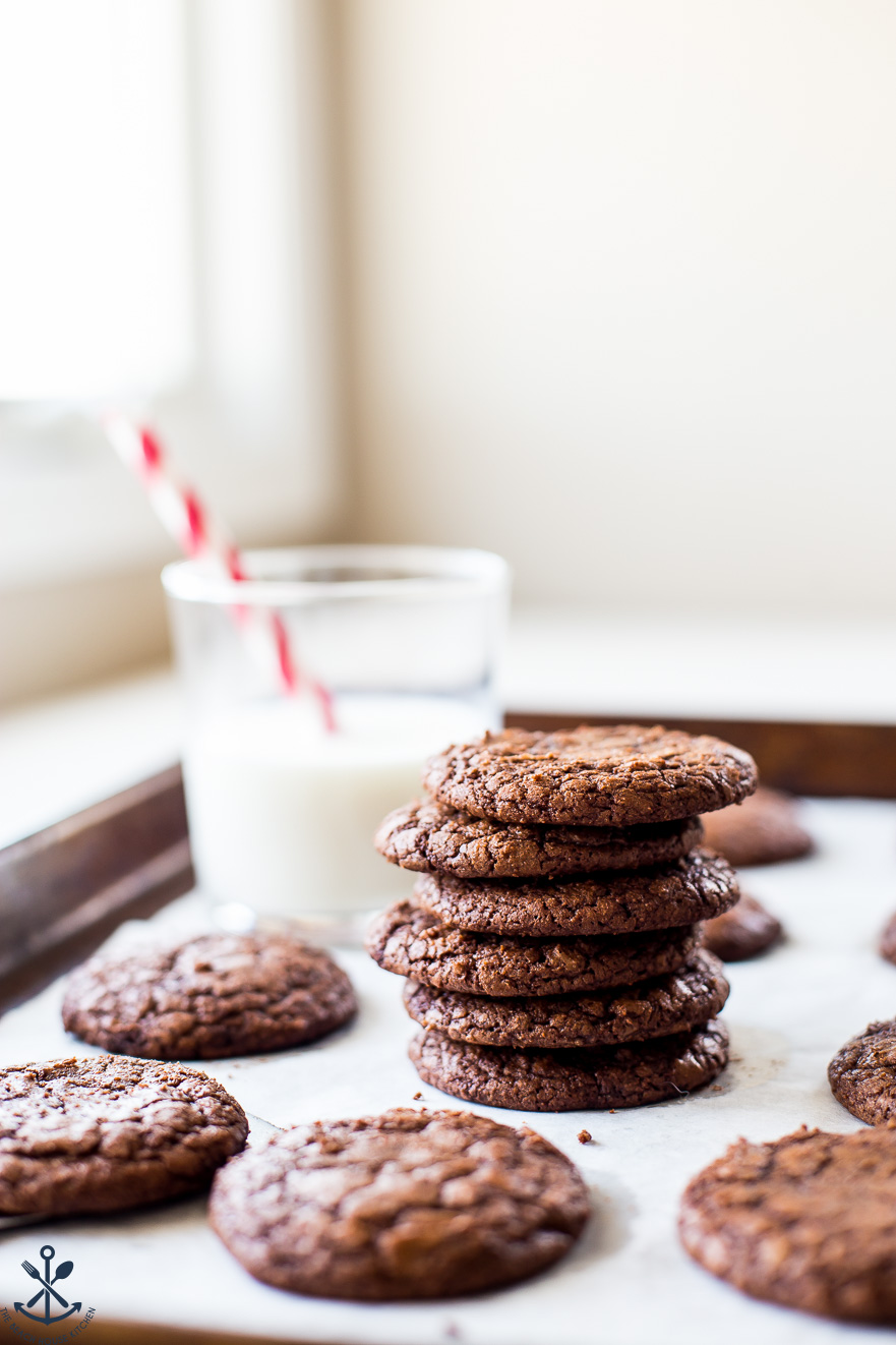 A stack of brownie cookies with a glass of milk in the background