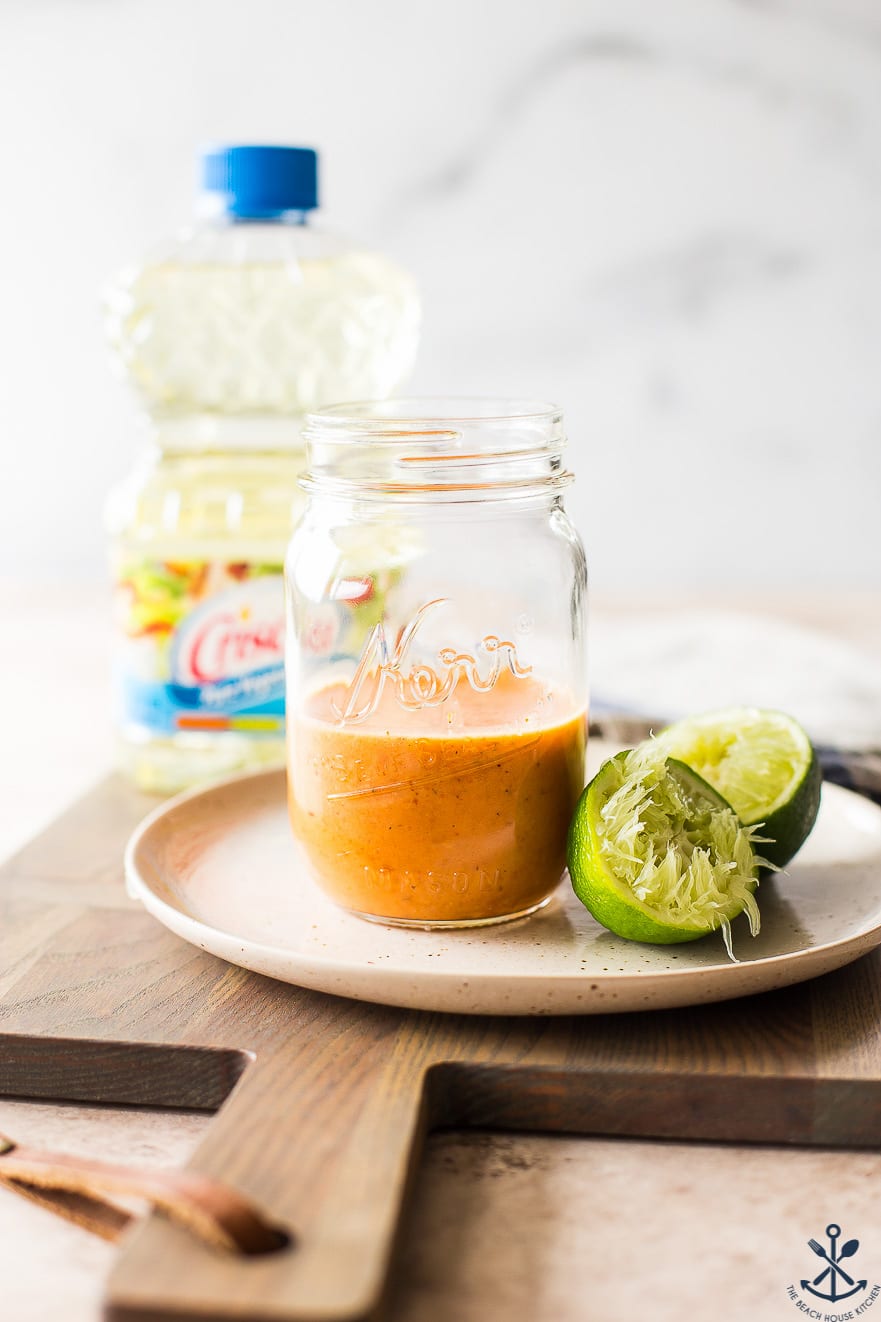 A dish with a jar of chipotle dressing and a juiced lime halved