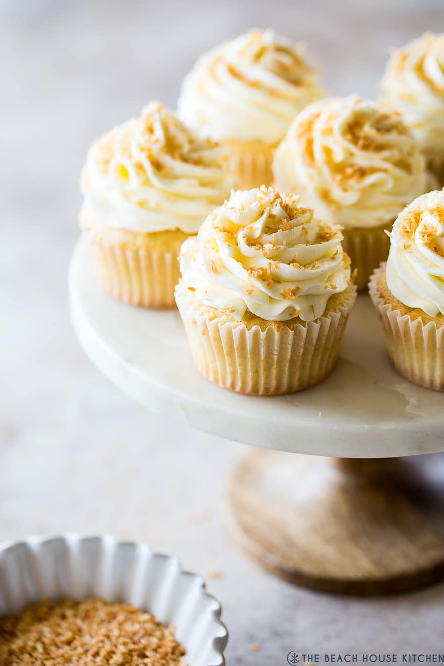 Cupcakes topped with toasted coconut on a cake stand