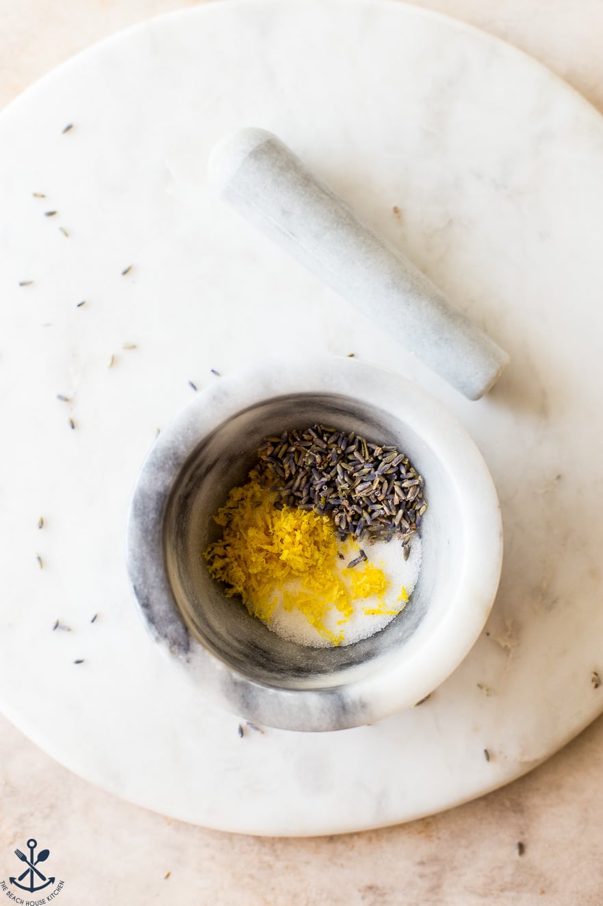 Overhead photo of a bowl filled with sugar, lemon zest and lavender buds