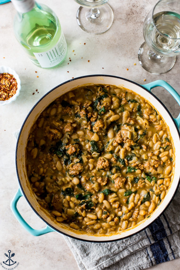 Overhead photo of a white bean sausage stew in a round Dutch oven
