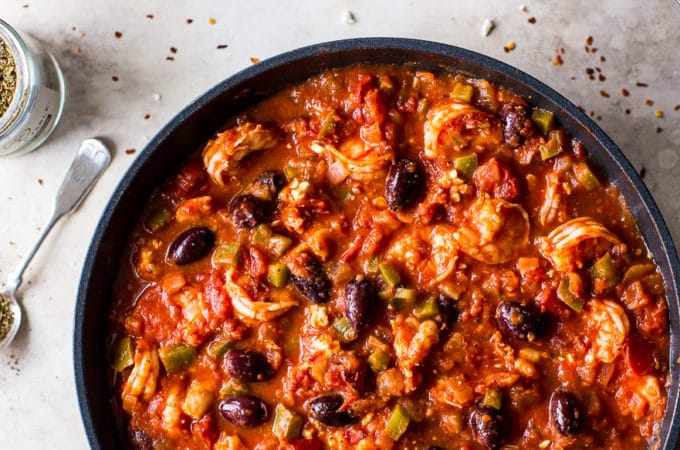 Overhead photo of a skillet with with a shrimp mixture with tomato sauce and olives