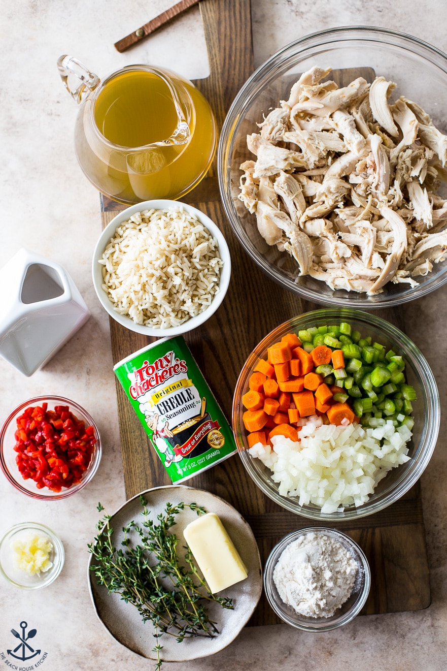 Overhead photo of ingredients for chicken rice soup in bowls on a wooden board