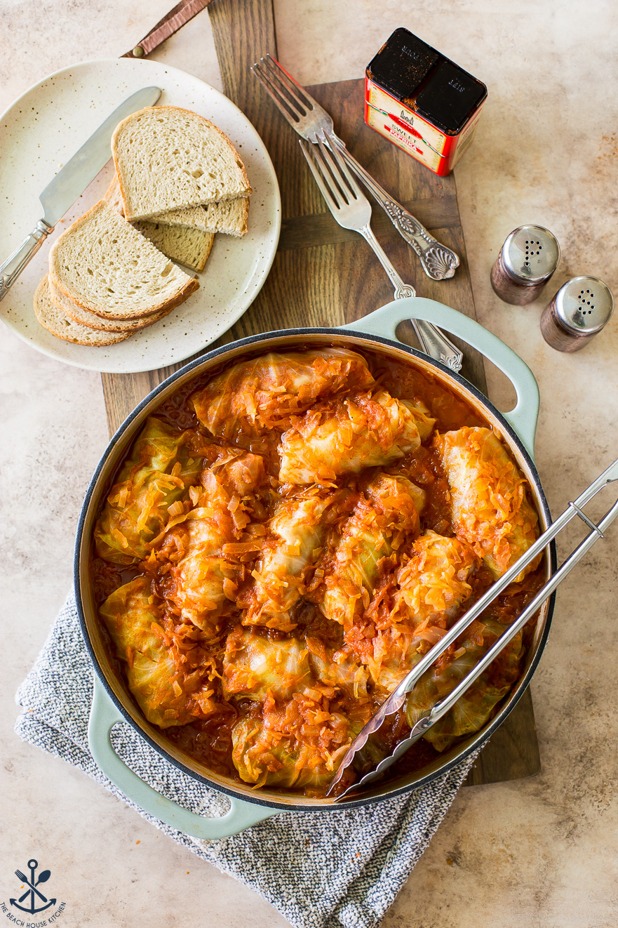 Overhead photo of stuffed cabbage in a baking dish with a plate of rye bread slices off to the side.