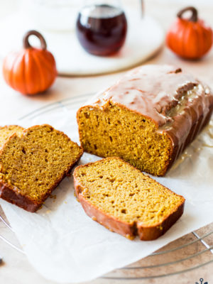 A loaf of pumpkin bread with a maple glaze with two slices
