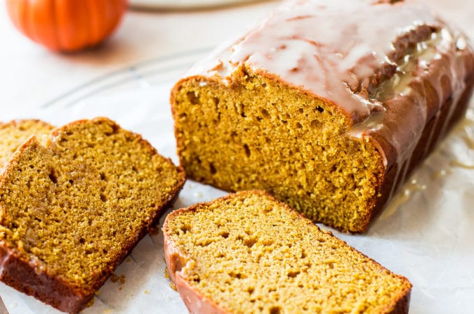 A loaf of pumpkin bread with a maple glaze with two slices