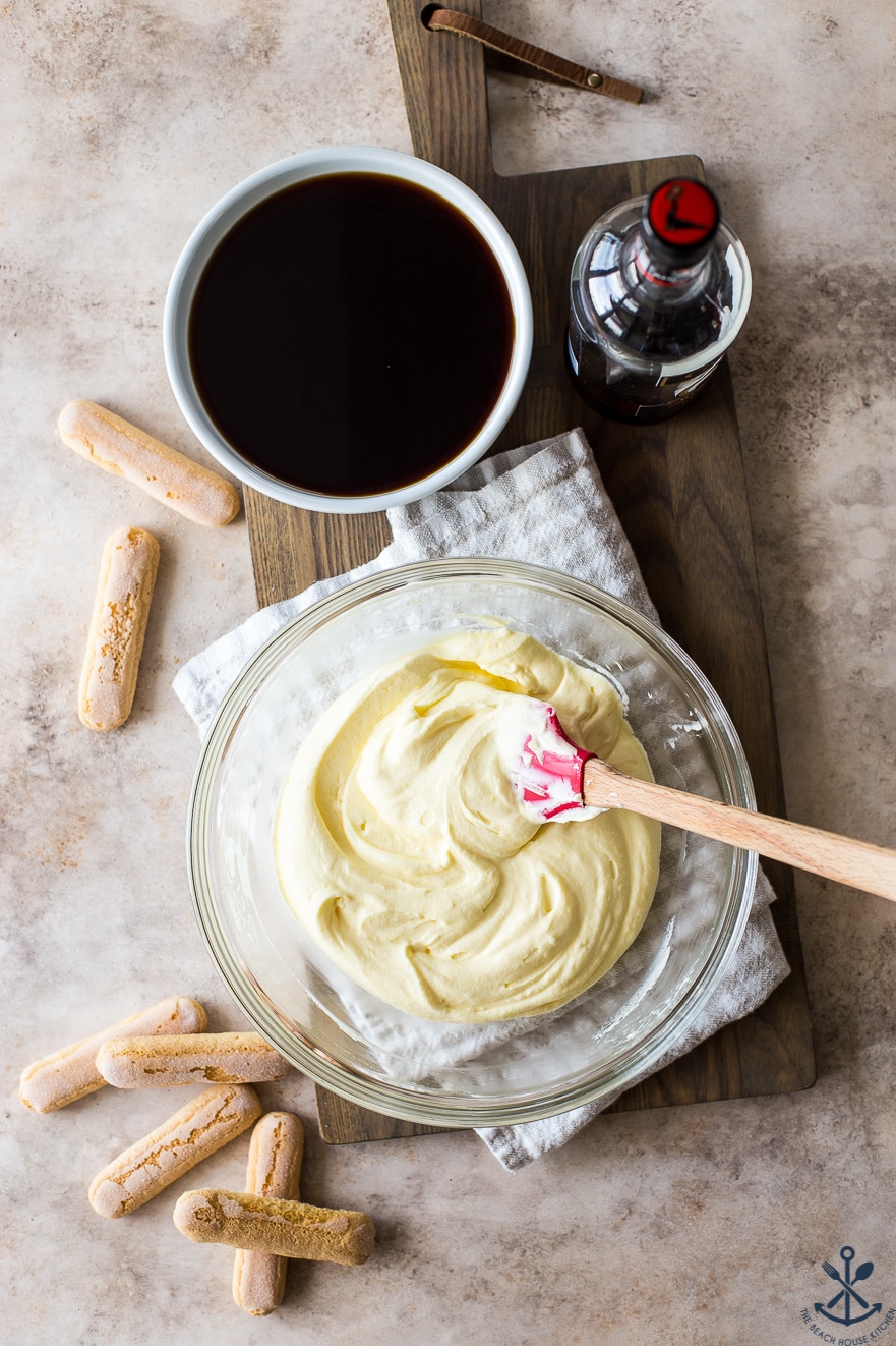 Overhead photo of a glass bowl of a mascarpone cream mixture and a white bowl of coffee