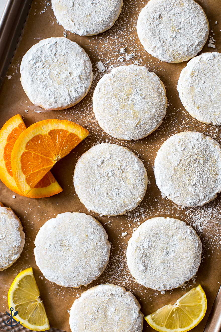 Up close overhead photo of powdered sugar covered cookies with orange and lemon slices