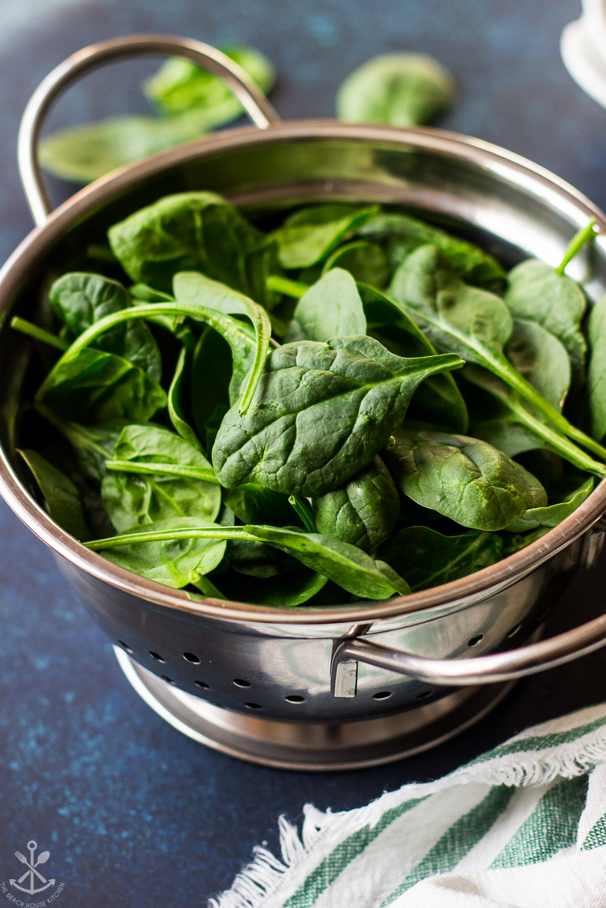 A colander filled with baby spinach leaves