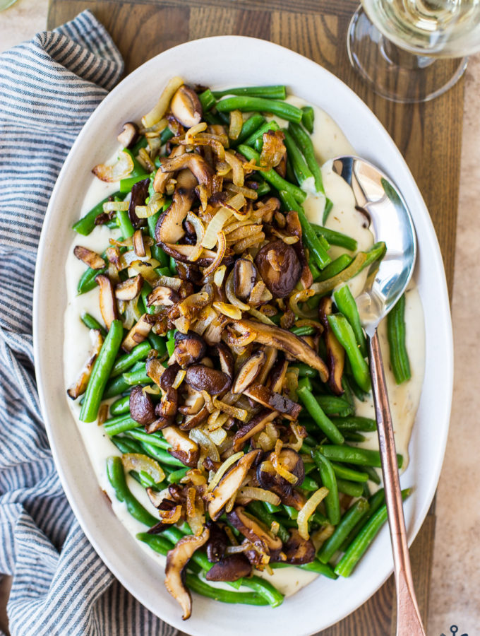 Up close overhead photo of oval plate of green beans topped with mushrooms and onions