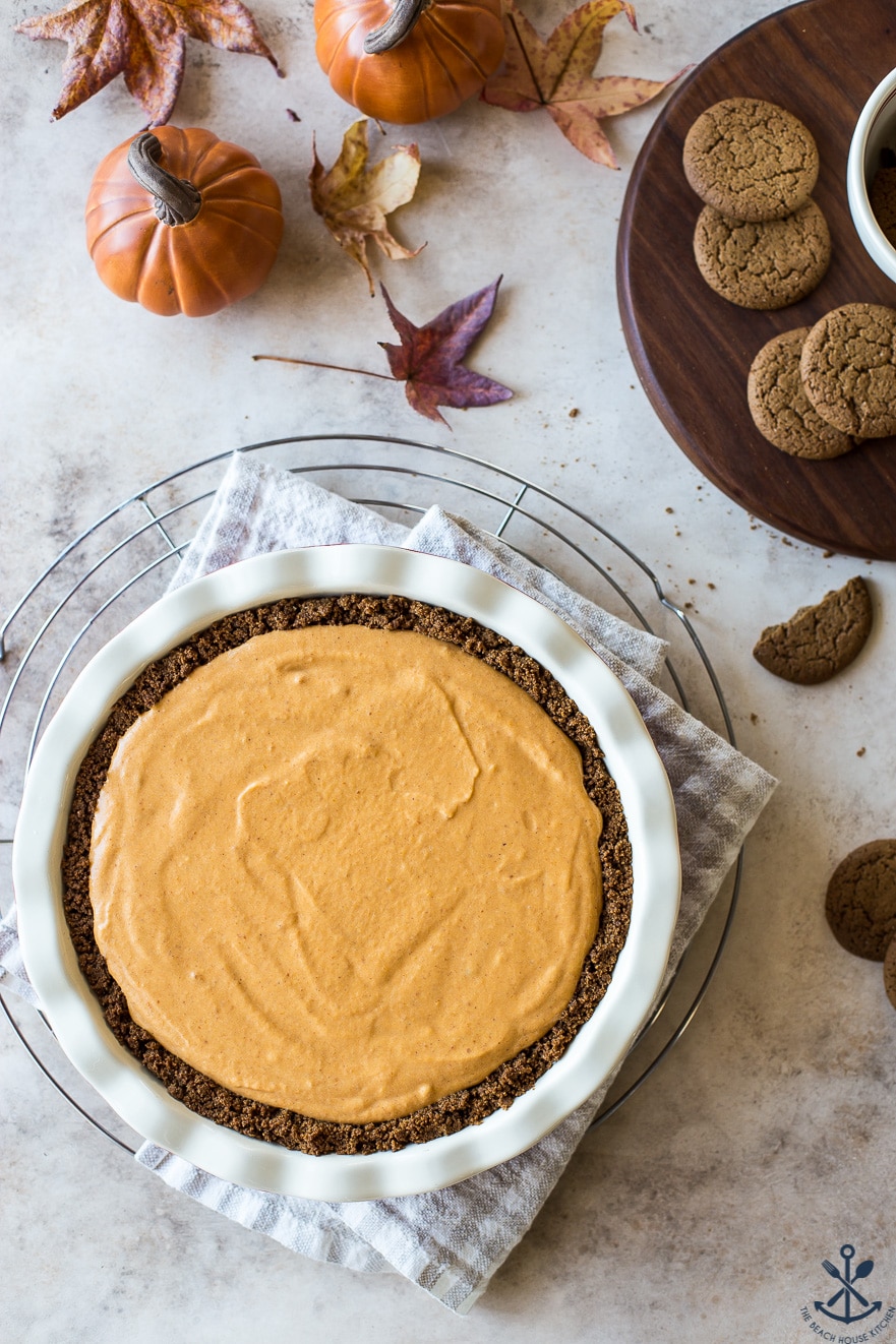 Overhead photo of a pumpkin chiffon pie on a wire rack with a board of gingersnaps off to the side