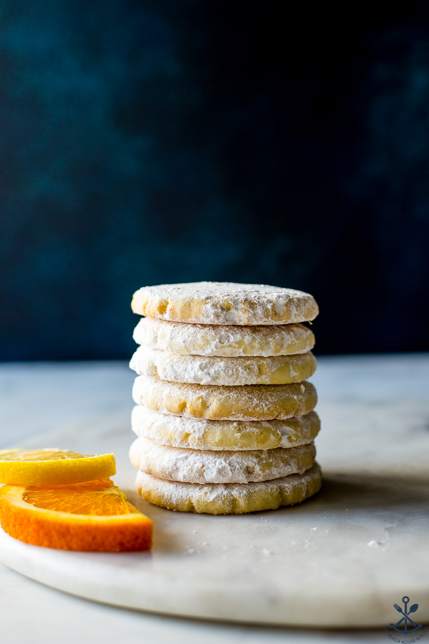 A stack of citrus meltaways on a round marble board with two orange slices
