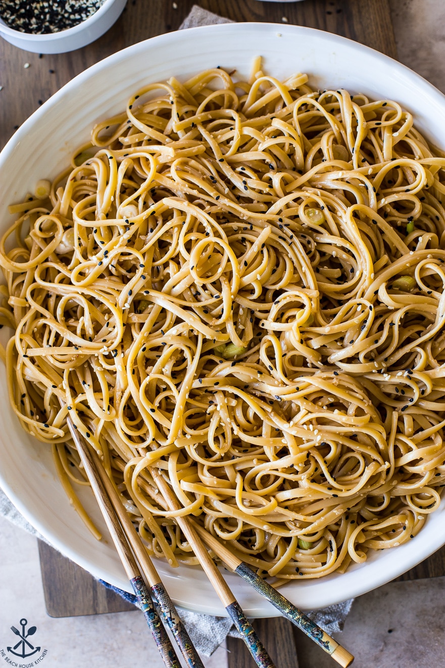 Up close overhead photo of a large bowl of sesame noodles with a set of chopsticks