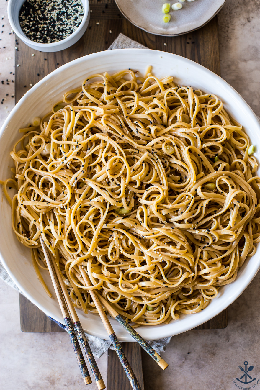 Overhead photo of a round white dish of sesame noodles with chopsticks
