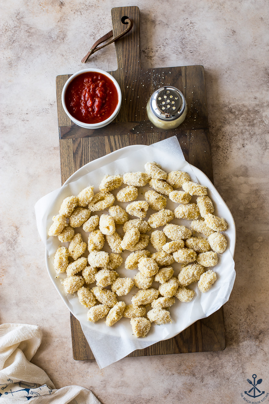 Overhead photo of pre-fried gnocchi bites on a parchment lined plate